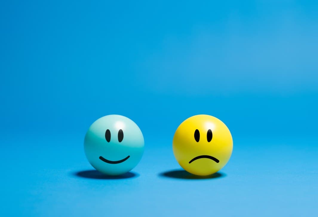 Two balls on a blue background: one smiling, one sad